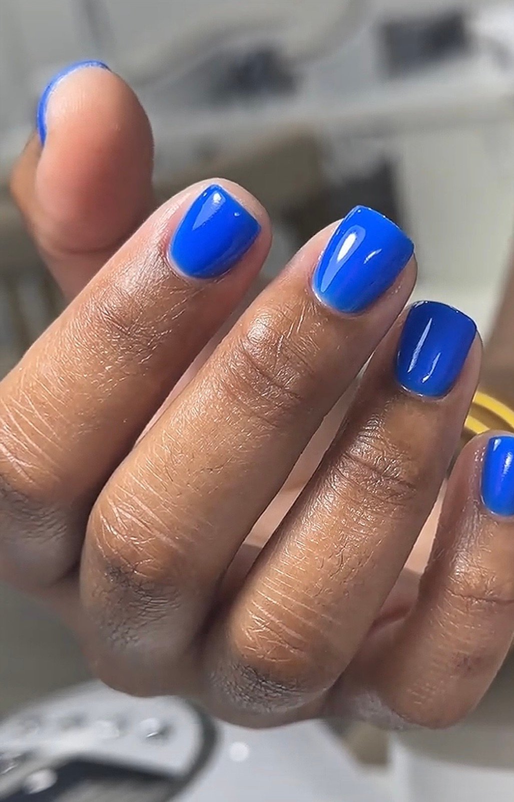 Nail design inspiration for hard gel extensions Tampa: Close-up of a hand with five blue square nails showing glossy finish and professional manicure