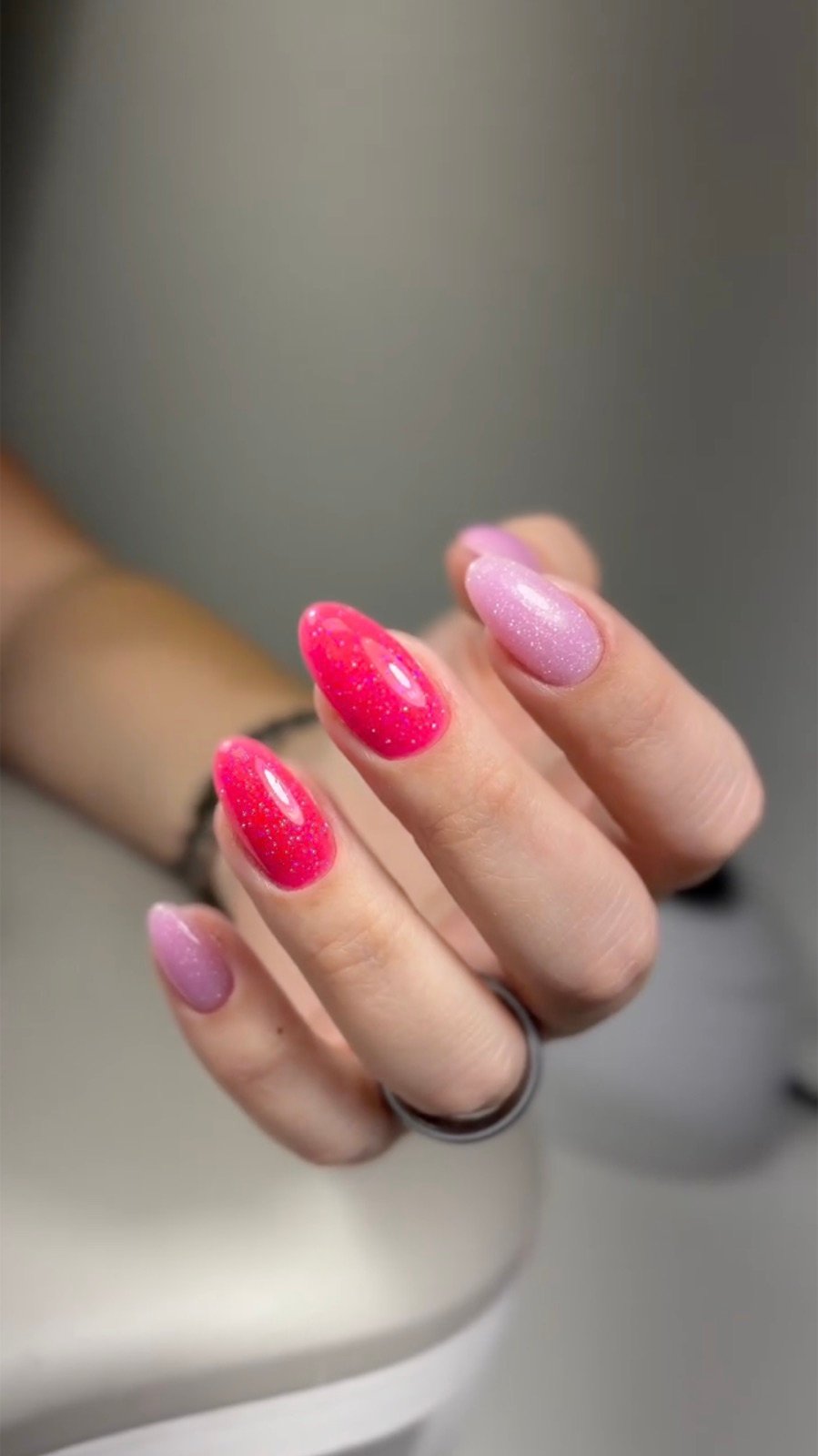 Nail design inspiration for russian manicure: Close-up of a hand with pink and purple glittery manicure showing gradient design and glossy finish