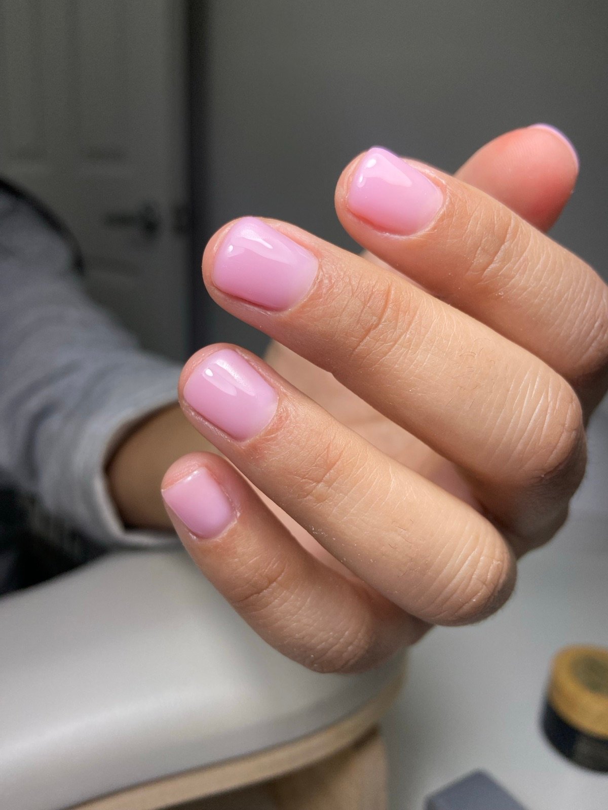 Nail design inspiration for russian manicure: Close-up of a hand with professionally applied soft pink square-shaped medium-length nails featuring a glossy finish, displayed
