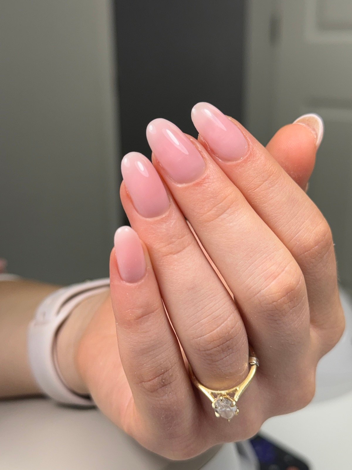 Nail design inspiration for russian nail salon near me: Close-up of a hand with soft pink gradient manicure showing smooth glossy nails and natural nail beds