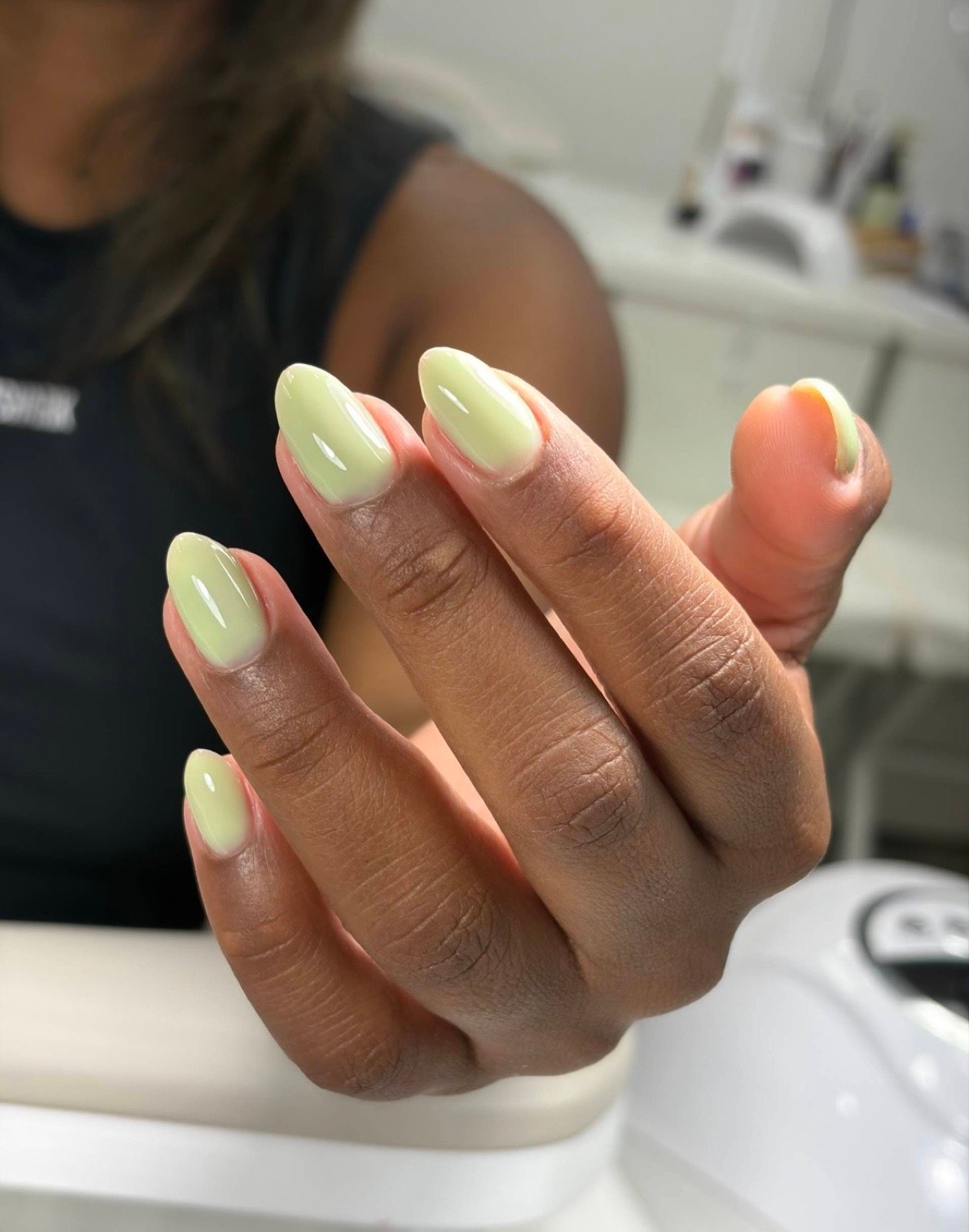Nail design inspiration for russian nail salon: Close-up of a hand with neatly manicured pale green oval nails in a salon setting
