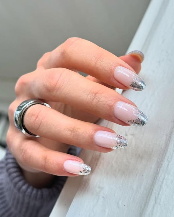 Nude oval manicure with softly faded silver glitter French tips