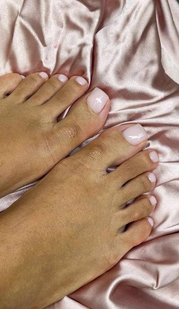 Pale blush pink gel pedicure photographed on satin fabric
